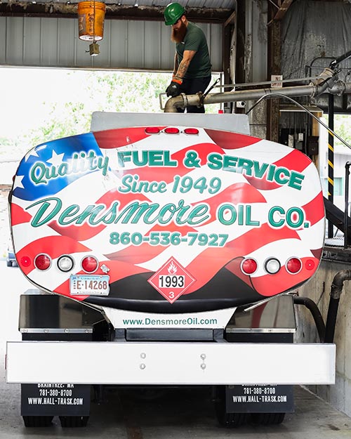 Delivery driver filling Densmore Oil's flag truck